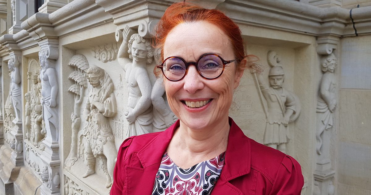 Portraitfoto Gabriele Diewald, rothaarige Frau mit Pferdeschwanz und runder Hornbrille