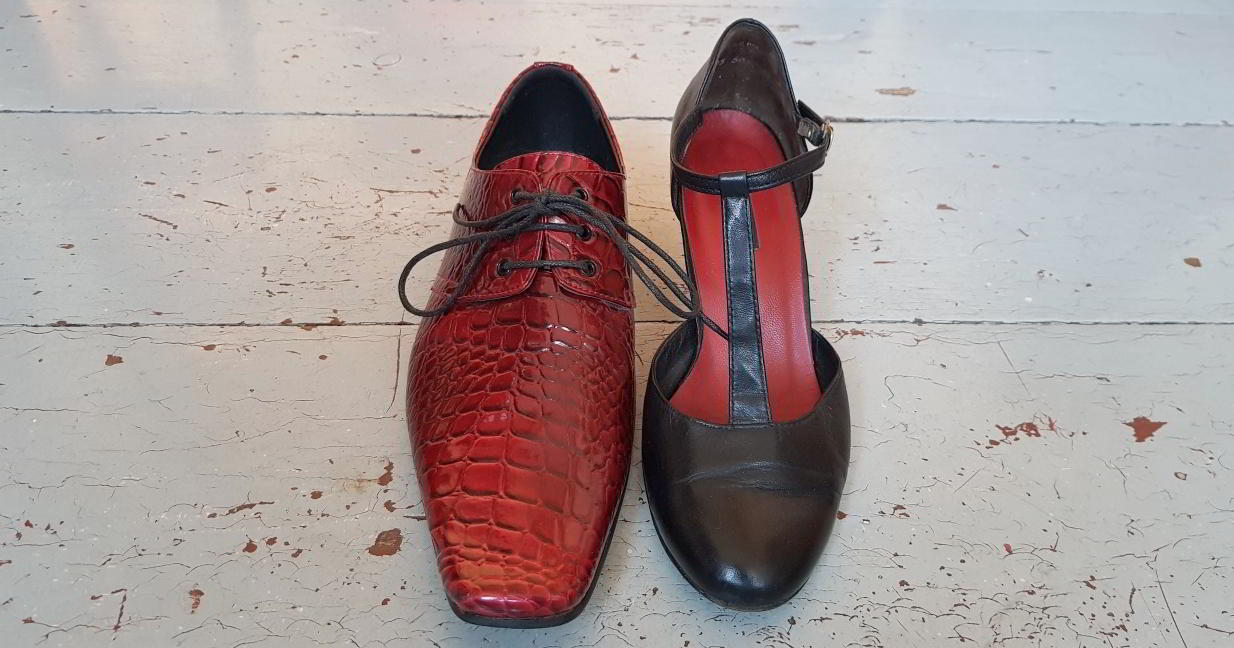 Ein roter Herrenschuh und ein schwarzer Damenschuh stehen nebeneinander
