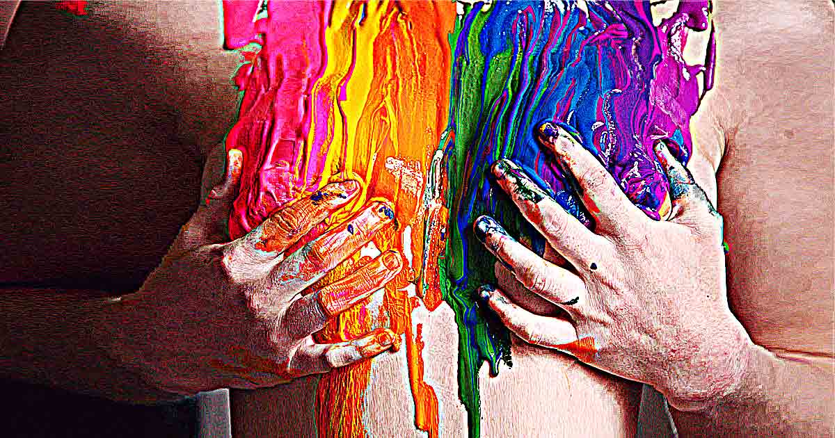 Hände verdecken eine Brust, die mit Fingerfarbe in den Tönen des Regenbogens beschmiert ist