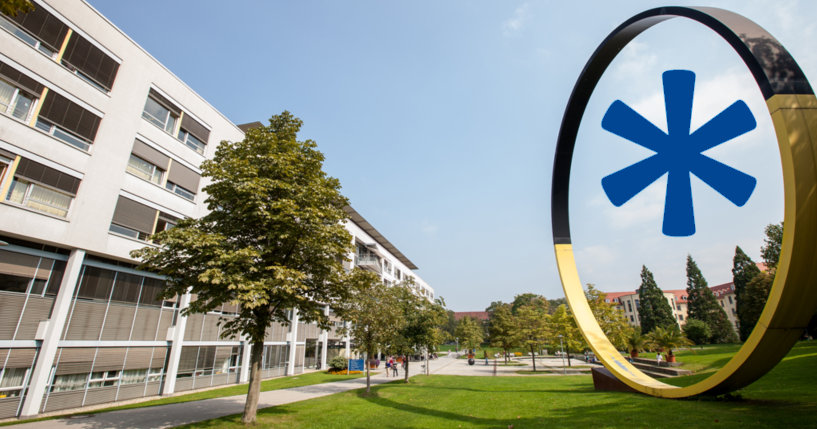 Neubau des Klinikums Freiburg mit Gartenanlage und einem aufgestellten Kreis als Kunstinstallation. Dahinein ist ein blauer Genderstern montiert.