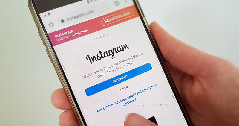 Smartphone in der Hand mit Instagram-Anmeldeoberfläche im Display