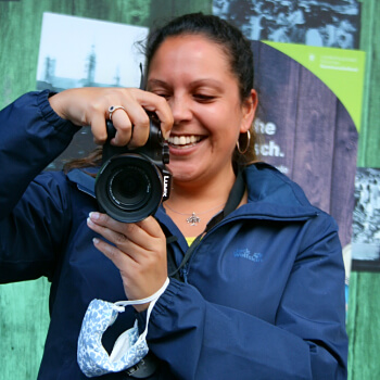 Portrait: Selinah Doulah hält eine Kamera in der Hand und lacht