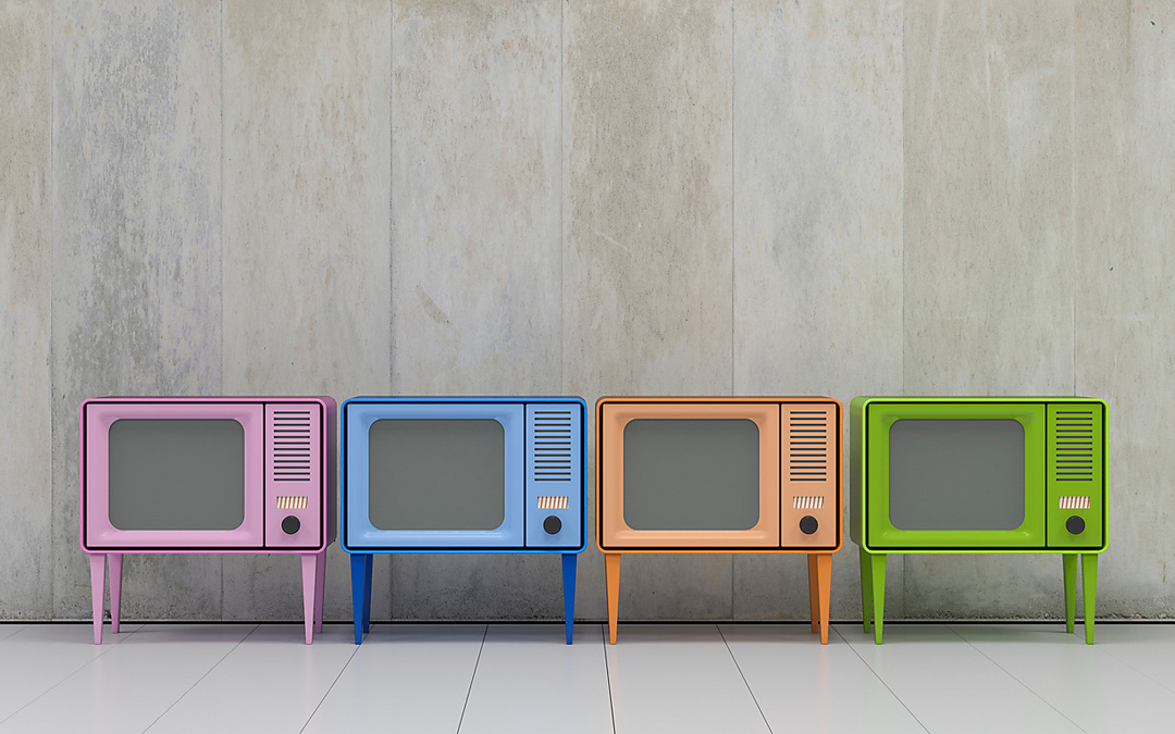 Vier bunte Fernseherchen stehen vor einer grauen Wand