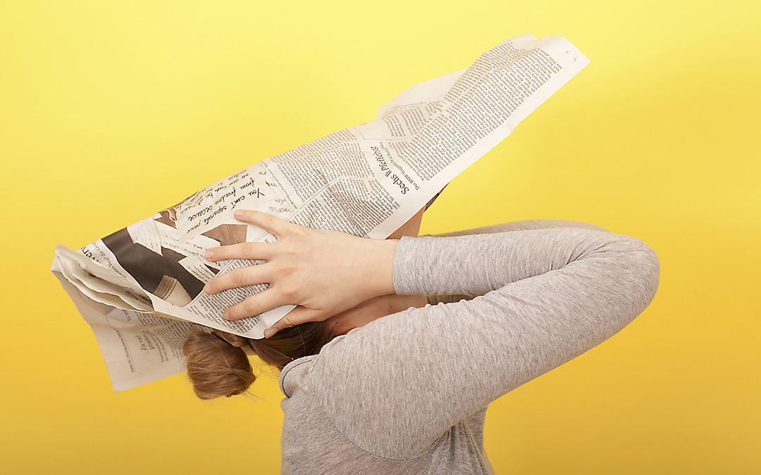 Frau bedeckt ihren Kopf mit einer Zeitung