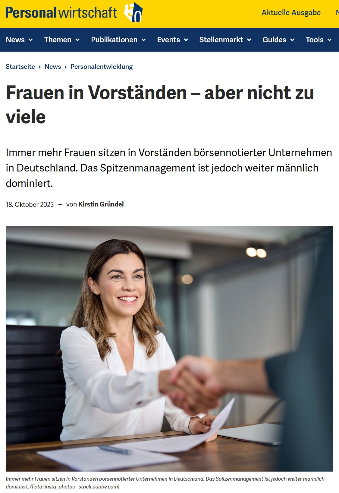 Junge Frau sitzt an einem Schreibtisch und schüttelt einer nicht sichtbaren Person die Hand