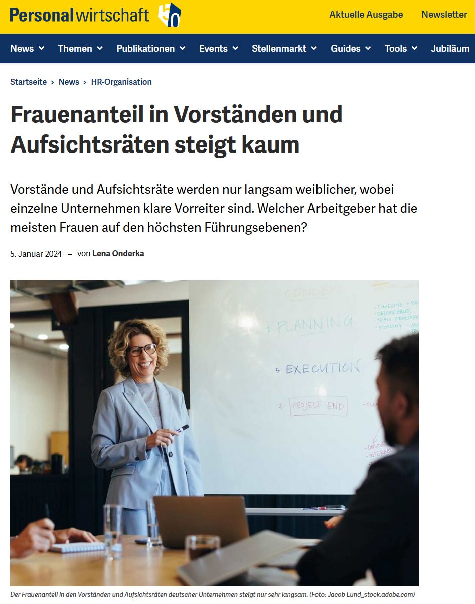 Im Büro: Eine Frau im hellblauen Kostüm im mittleren Alter spricht freundlich mit einem Mitarbeiter 