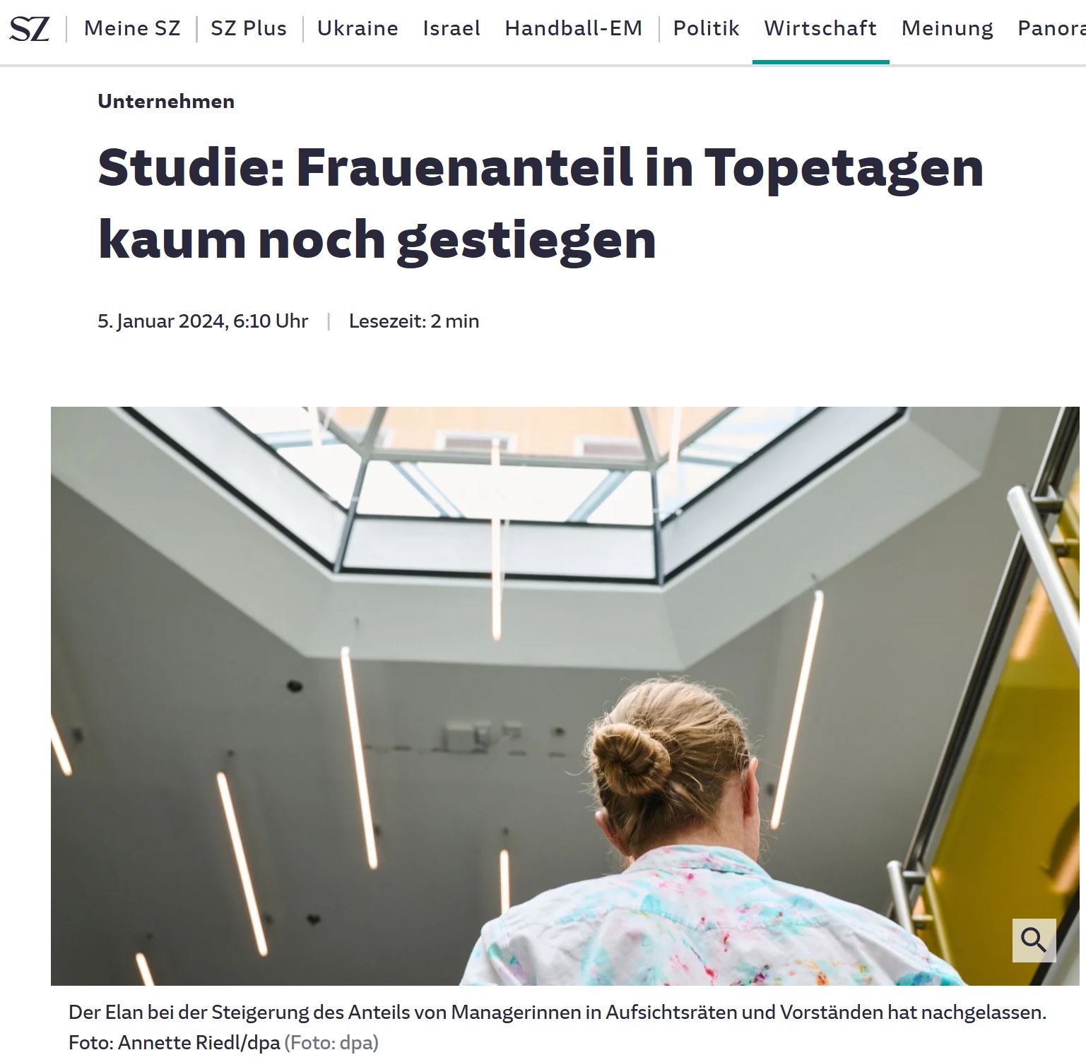 Screenshot: Rückenansicht jüngere Frau in bunter Bluse und Haarknoten