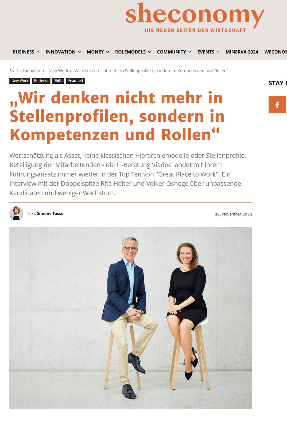 Ein Mann und eine Frau in Businesskleidung sitzen auf Barhockern und schauen in die Kamera