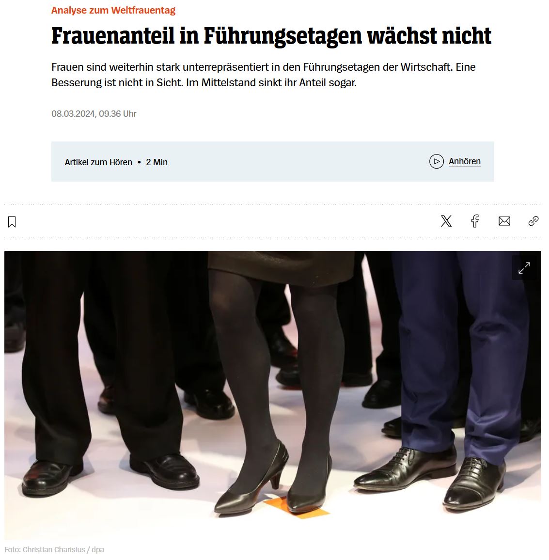 Fraubeine in schwarzen Strumpfhosen und mit schwarzen Pumps steht zwischen schwarzen Männerhosenbeinen 