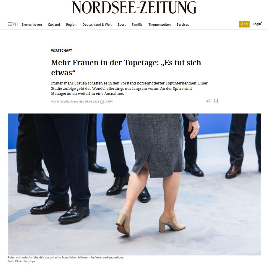 Blick auf den Po einer Frau im grauen Businessoutfit und die die Hosenbeine von sechs Männern.