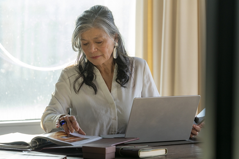 Chefin mit Laptop ©Anita Back Frau mit grauen Haaren arbeitet konzentriert am Schreibtisch