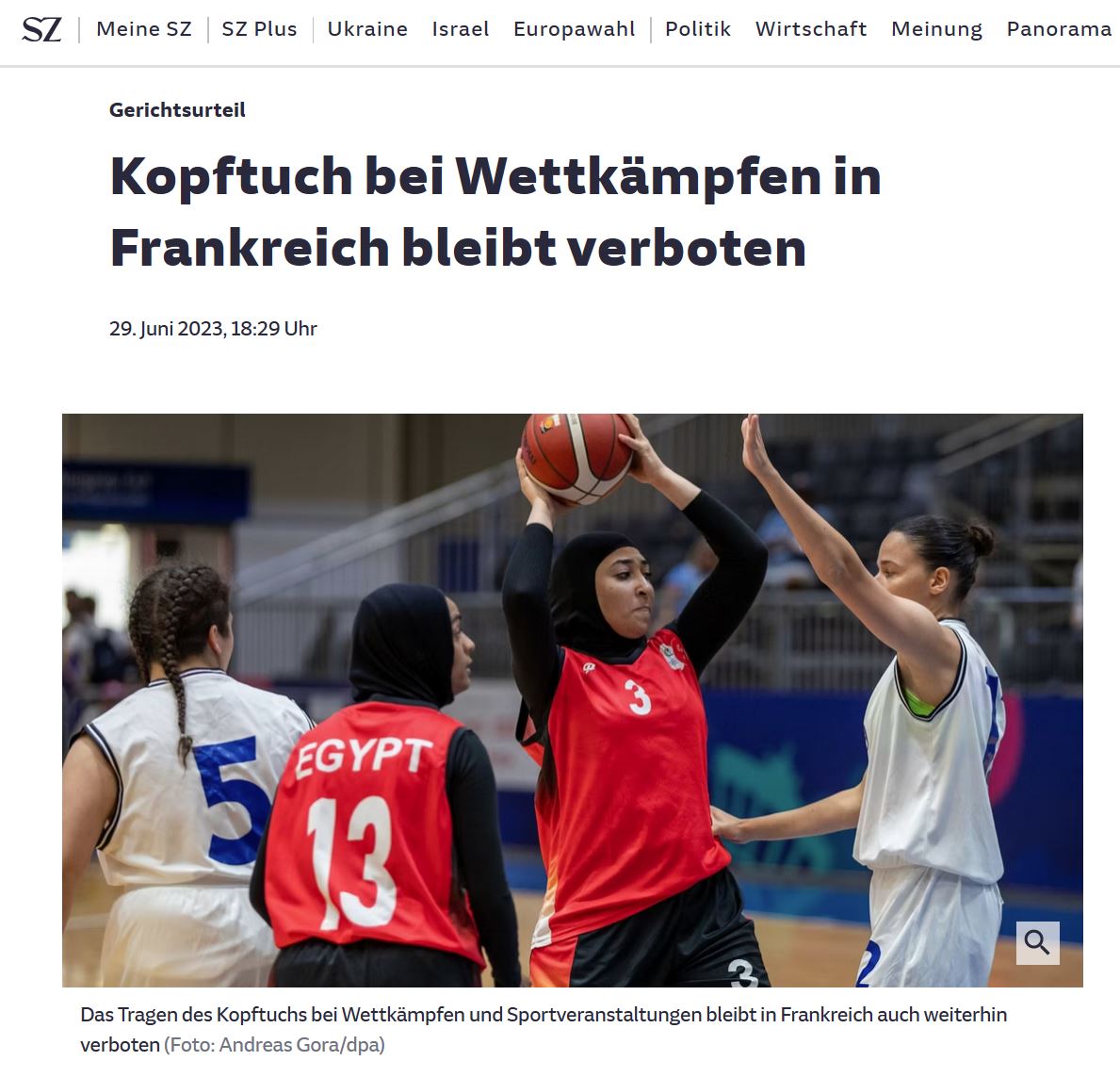 Basketballerinnen auf Spielfeld. Zwei Sportlerinnen aus Ägypten tragen ein schwarzes Trikot mit integrierter Kopftuchhaube.