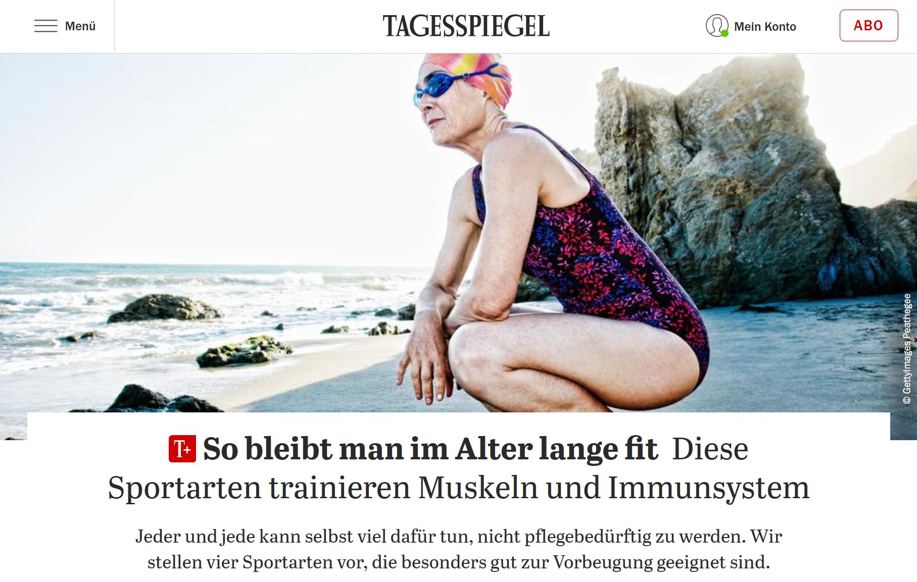 Eine ältere Frau im Badeanzug mit Schwimmkappe auf dem Kopf hockt an einem Strand. Sie ist schlank, aber an Hals und Händen erkennbar faltig.