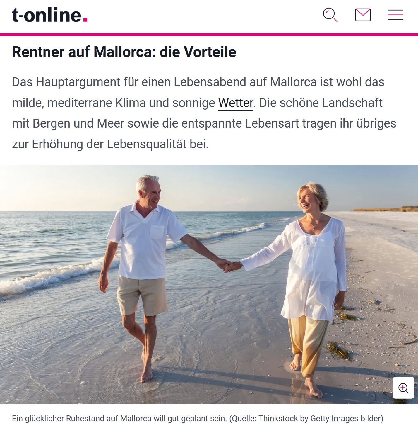 Ein attraktives, älteres Paar läuft in sommerlicher Kleidung lächelnd Hand in Hand an einem Strand entlang