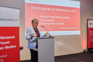 Eine Frau am Redepult, dahinter Schrifteinblendung Verleihung der jb-Medienpreise 2025