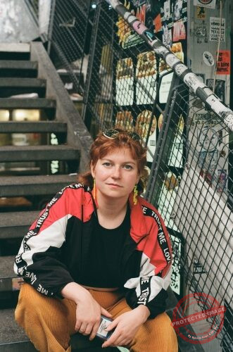 Junge Person mit roten Haaren sitzt auf einer Treppe